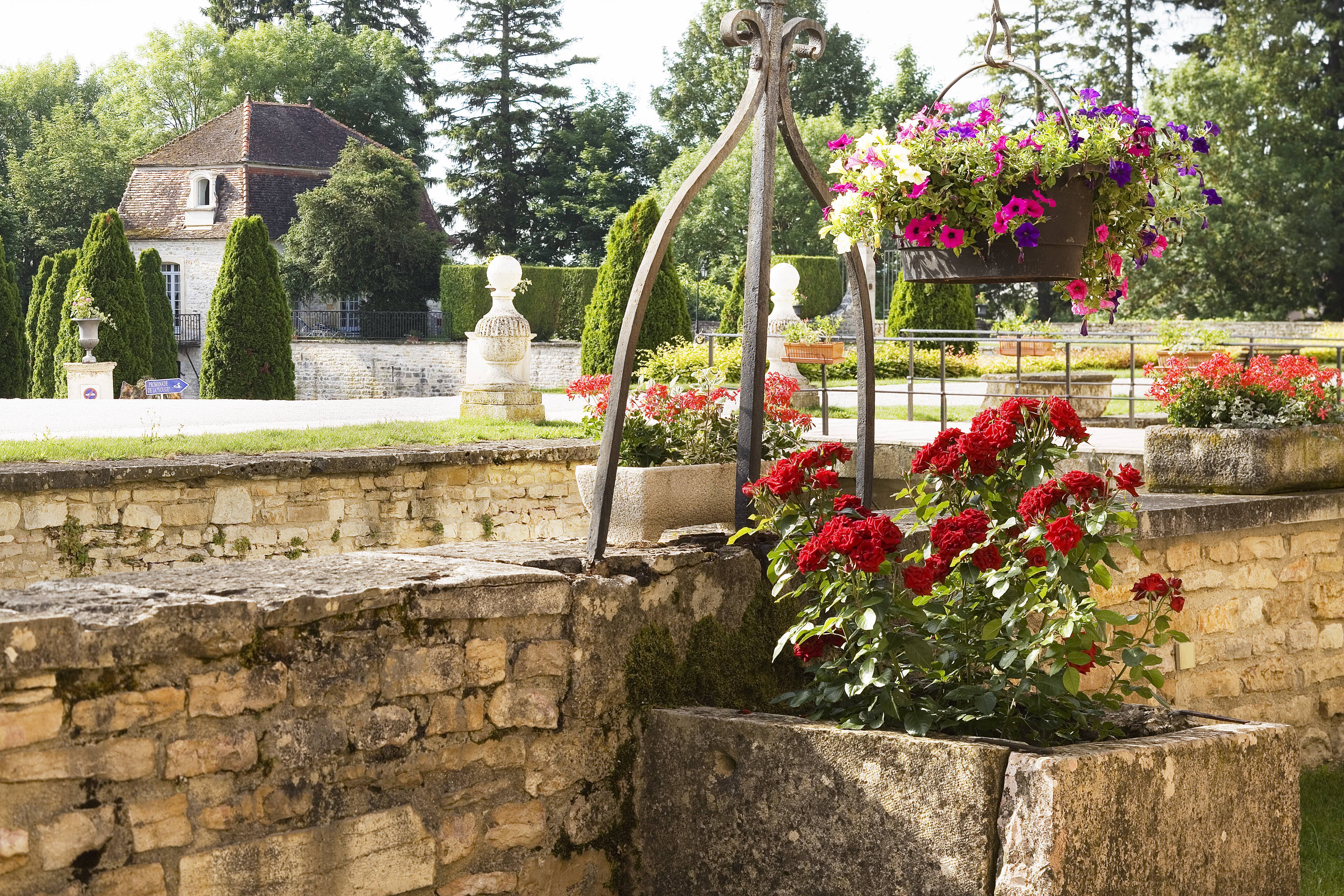 Chateau de Gilly gardens with red roses in stone tub