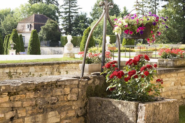 Chateau de Gilly gardens with red roses in stone tub