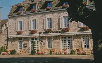 Le Montrachet Burgundy exterior stone building with shuttered windows and hanging baskets