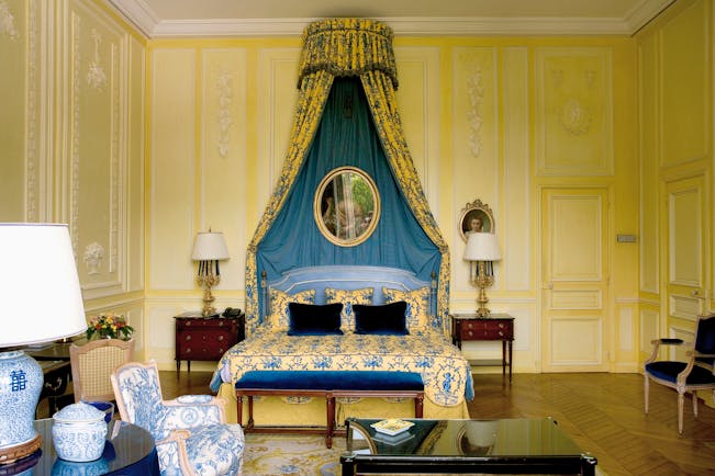 Bedroom with yellow and blue colour scheme, double bed and bed side tables with drapes
