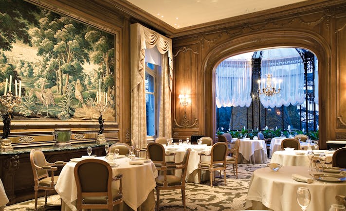 Restaurant with art work on the wall, tables set up and chandeliers 