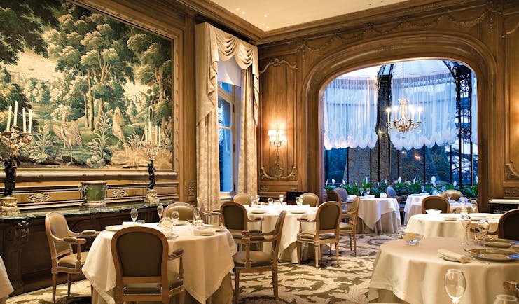 Restaurant with art work on the wall, tables set up and chandeliers