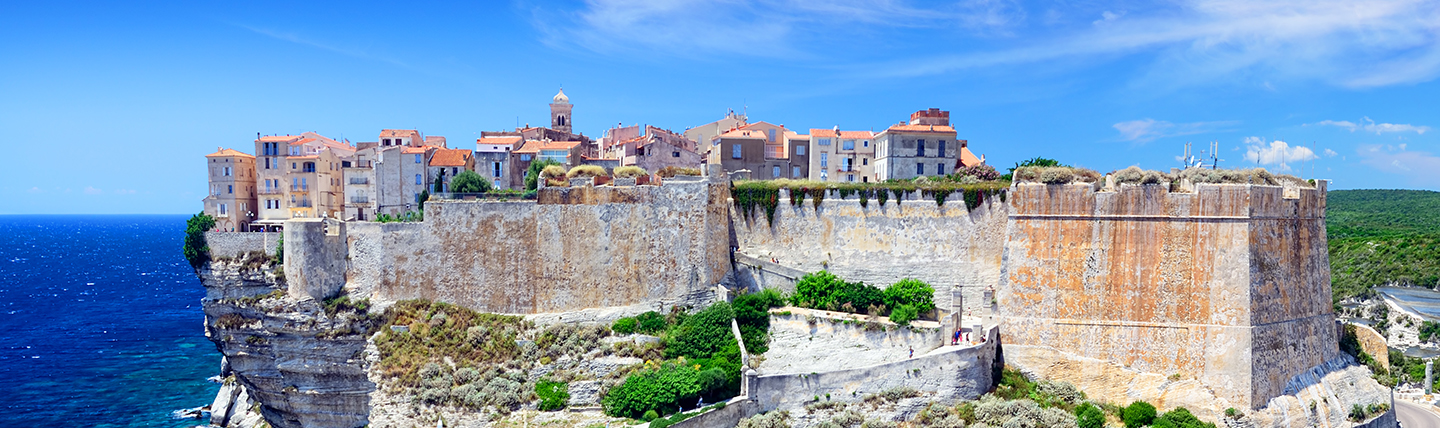 Old town and buildings fortified in pale stone on cliff above sea
