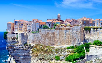 Old town and buildings fortified in pale stone on cliff above sea