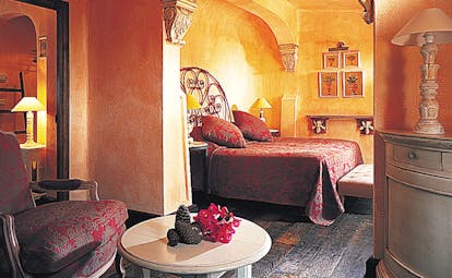 Grand Hotel de Cala Rossa Corsica bedroom with ornate armchair and wrought iron head board