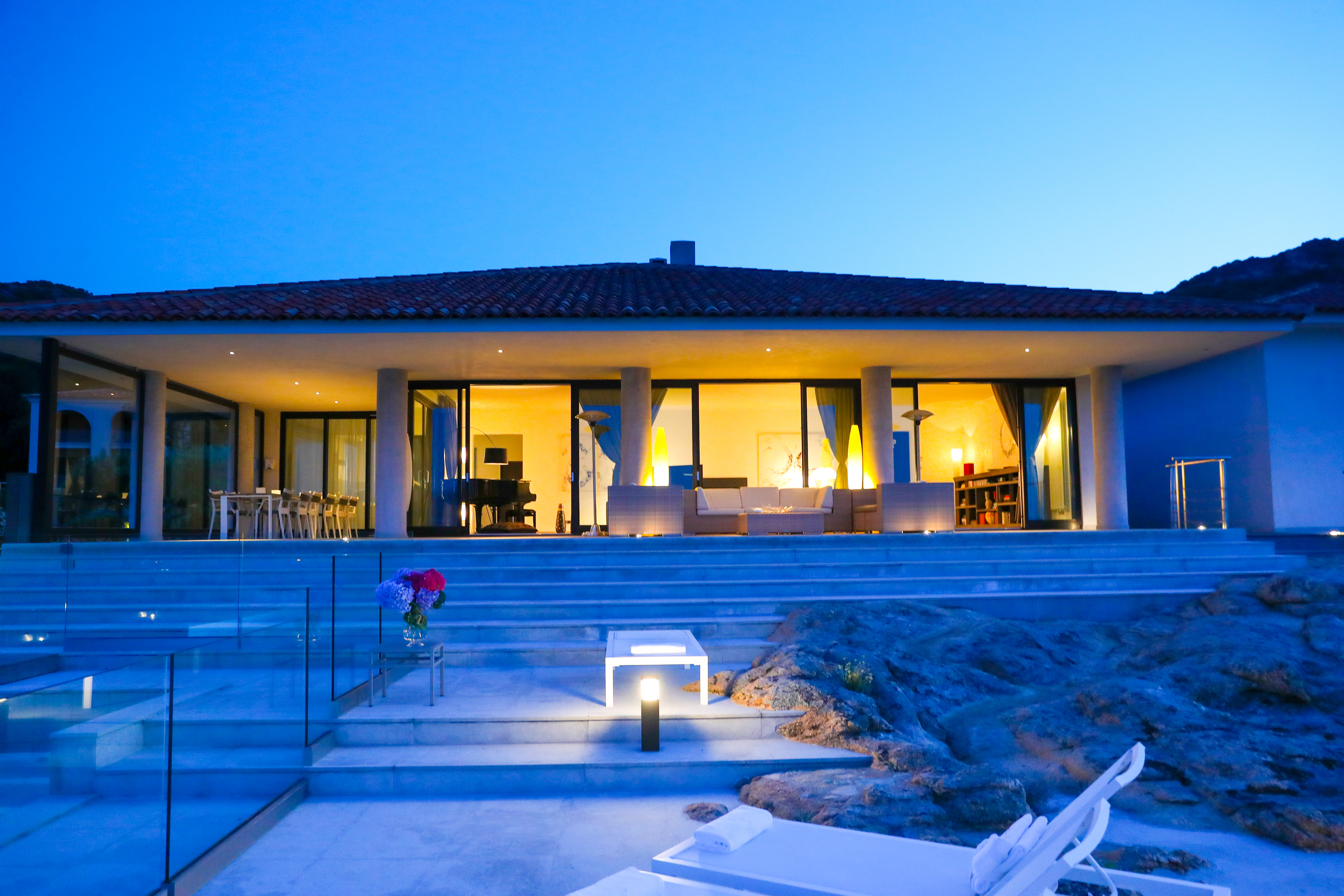 Exterior at night with steps leading up to the hotel and a piano shown inside