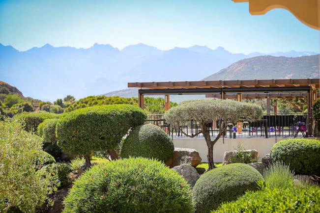 View of terrace amongst the gardens with hedges and trees in front and mountains in background