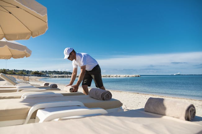 Le Cap d'Antibes Beach Hotel Cote d'Azur beach view man arranging towels on sun lounger