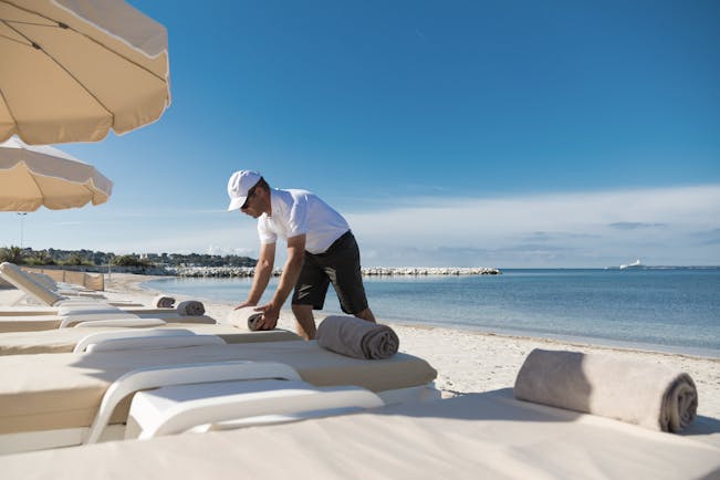 Le Cap d'Antibes Beach Hotel Cote d'Azur beach view man arranging towels on sun lounger