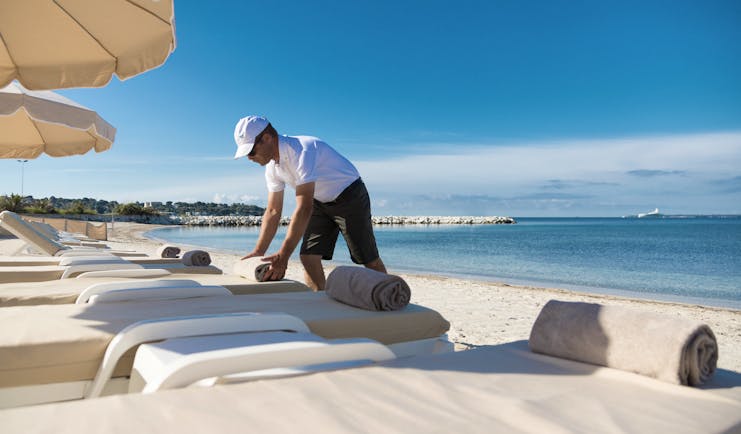 Le Cap d'Antibes Beach Hotel Cote d'Azur beach view man arranging towels on sun lounger