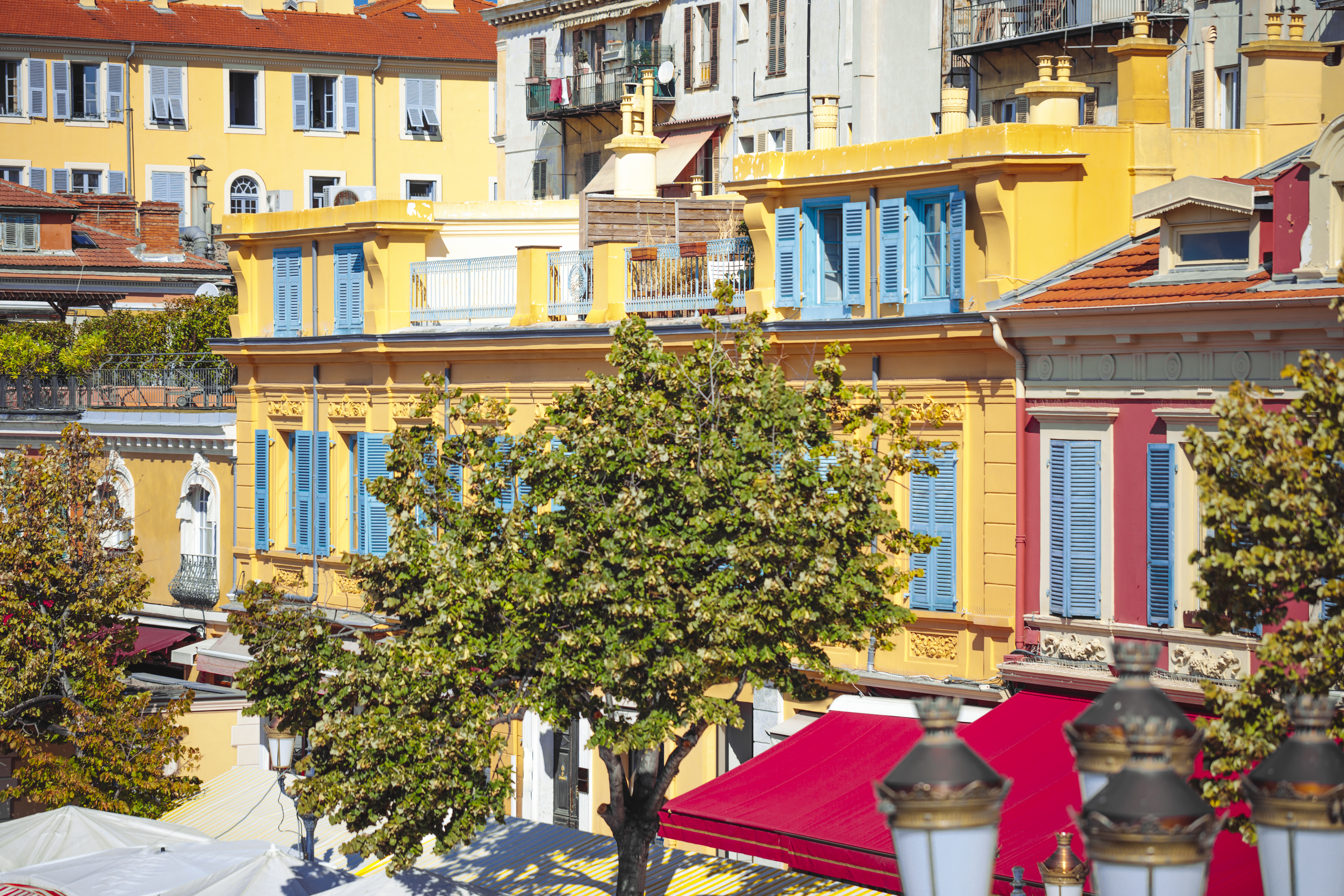 Yellow houses with blue shutters in flower market Nice