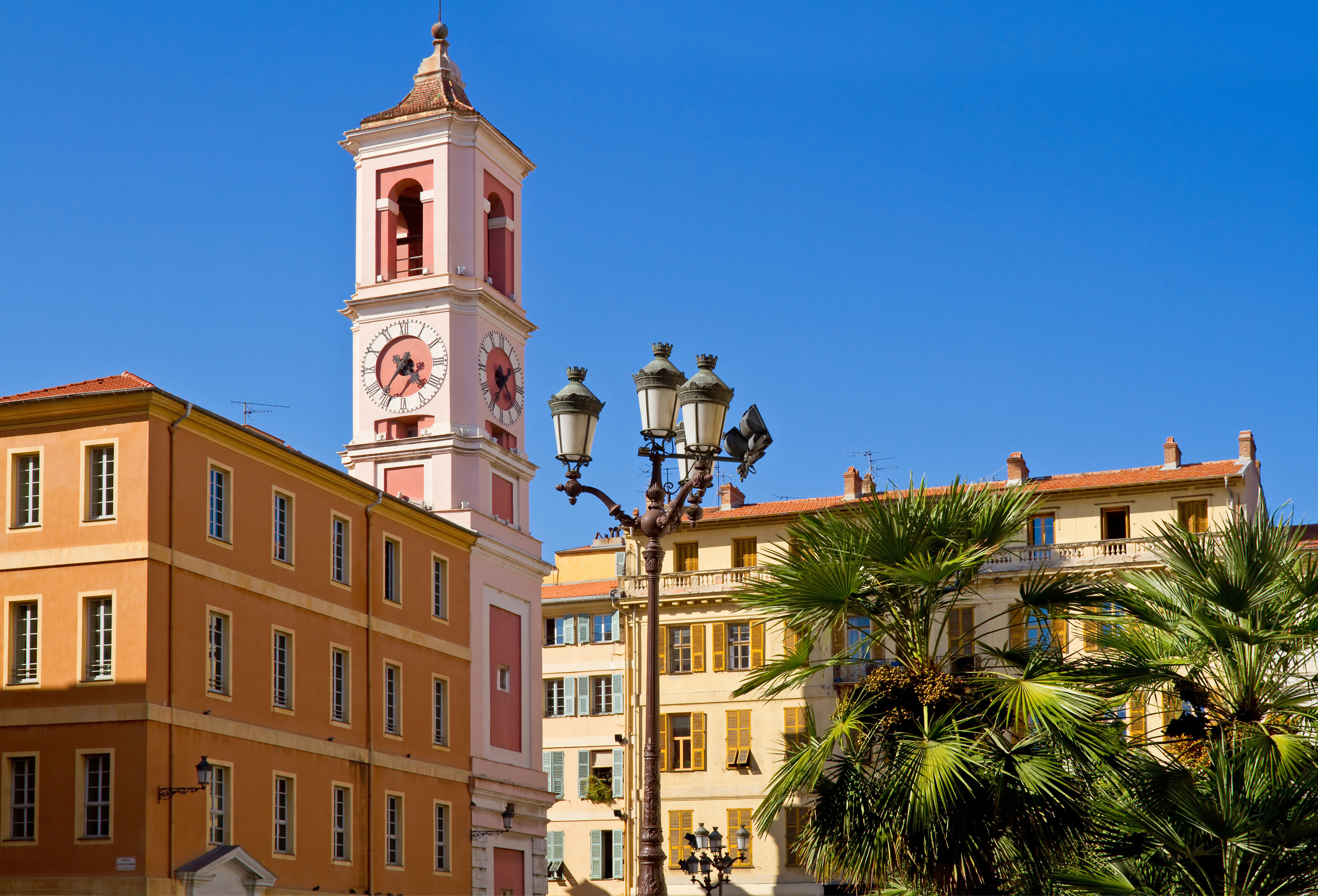 Old town Nice with yellow buildings and clock tower and palms