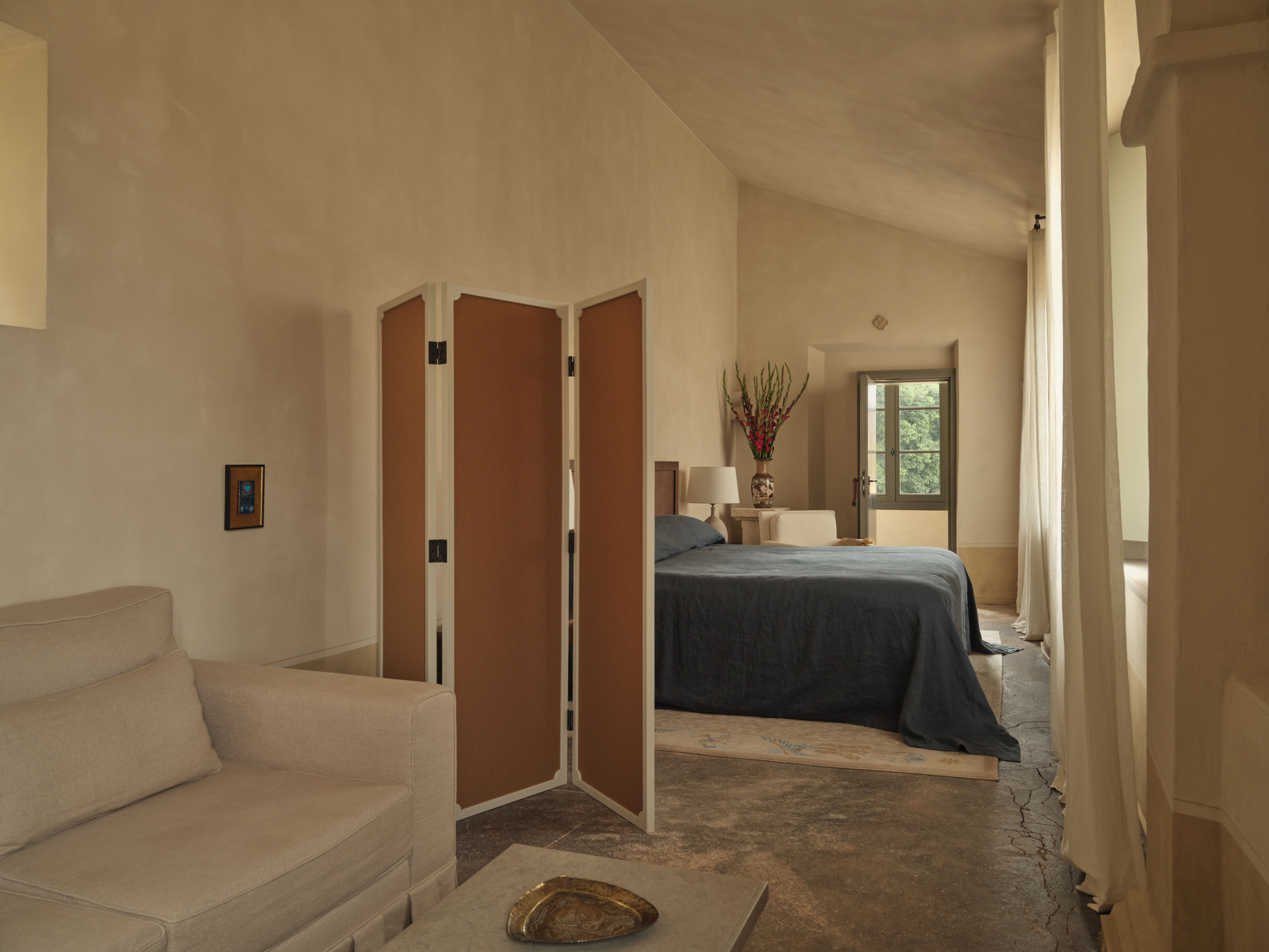 Hotel du Couvent bedroom with slanted roof, simple wooden room divider, and sofa and coffee table in the foreground