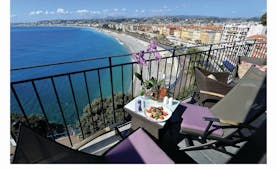 Hotel La Perouse Nice balcony overlooking the sea with two tables and chairs with a salad and flowers