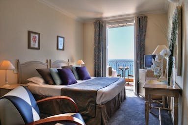 Hotel La Perouse Nice bedroom with a large window opening onto a balcony overlooking the sea
