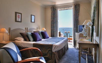 Hotel La Perouse Nice bedroom with a large window opening onto a balcony overlooking the sea