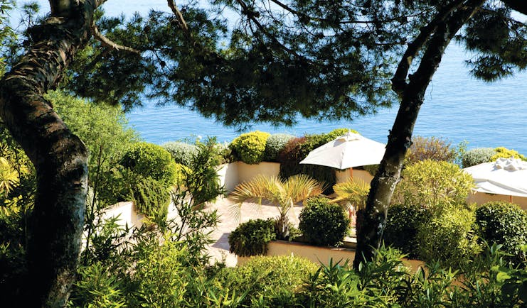 Hotel La Perouse Nice vista view of a walled patio surrounded by trees and shrubs overlooking the sea