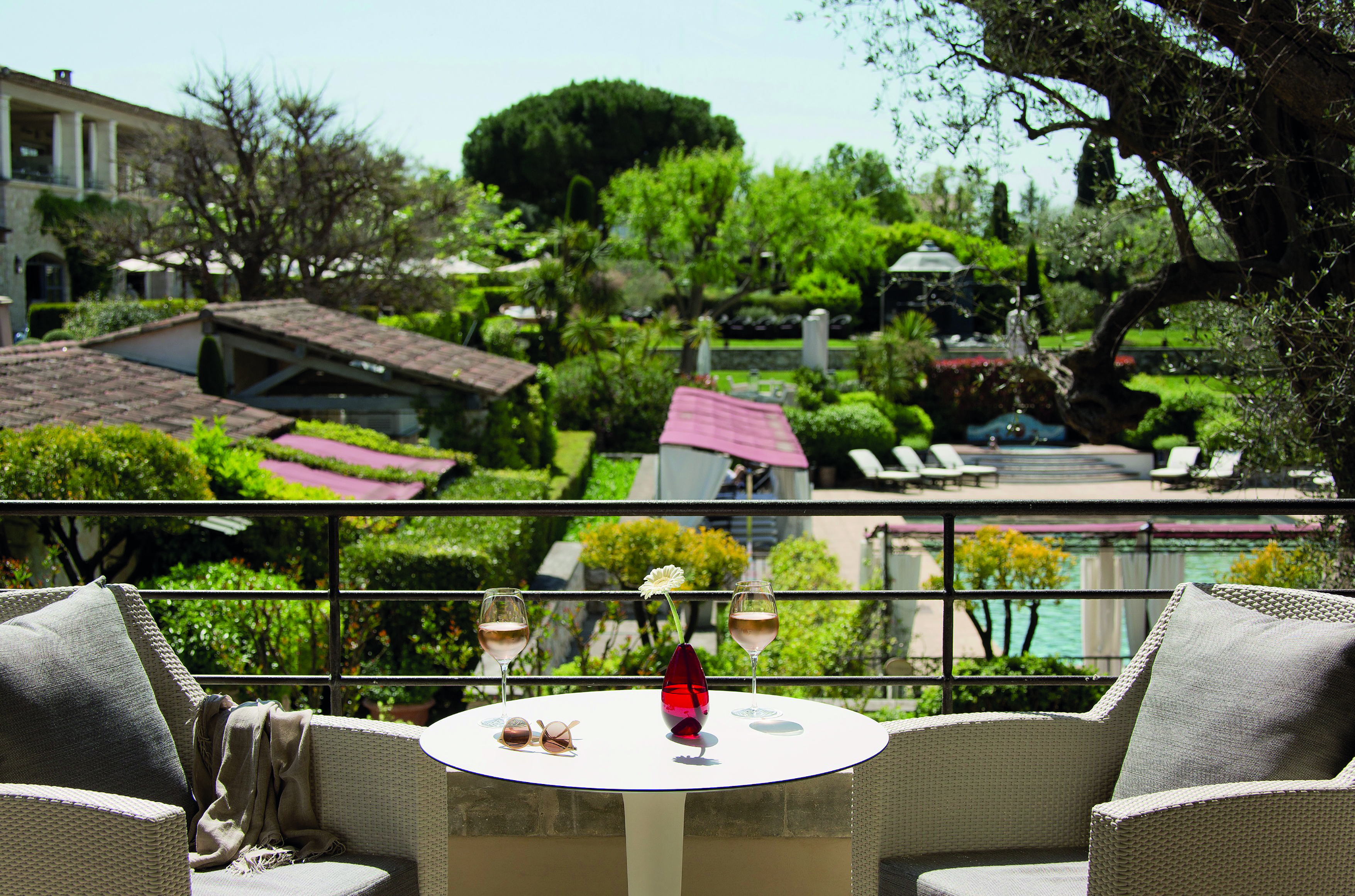 Le Mas de Pierre Cote d'Azur balcony with two chairs and a table overlooking a swimming pool