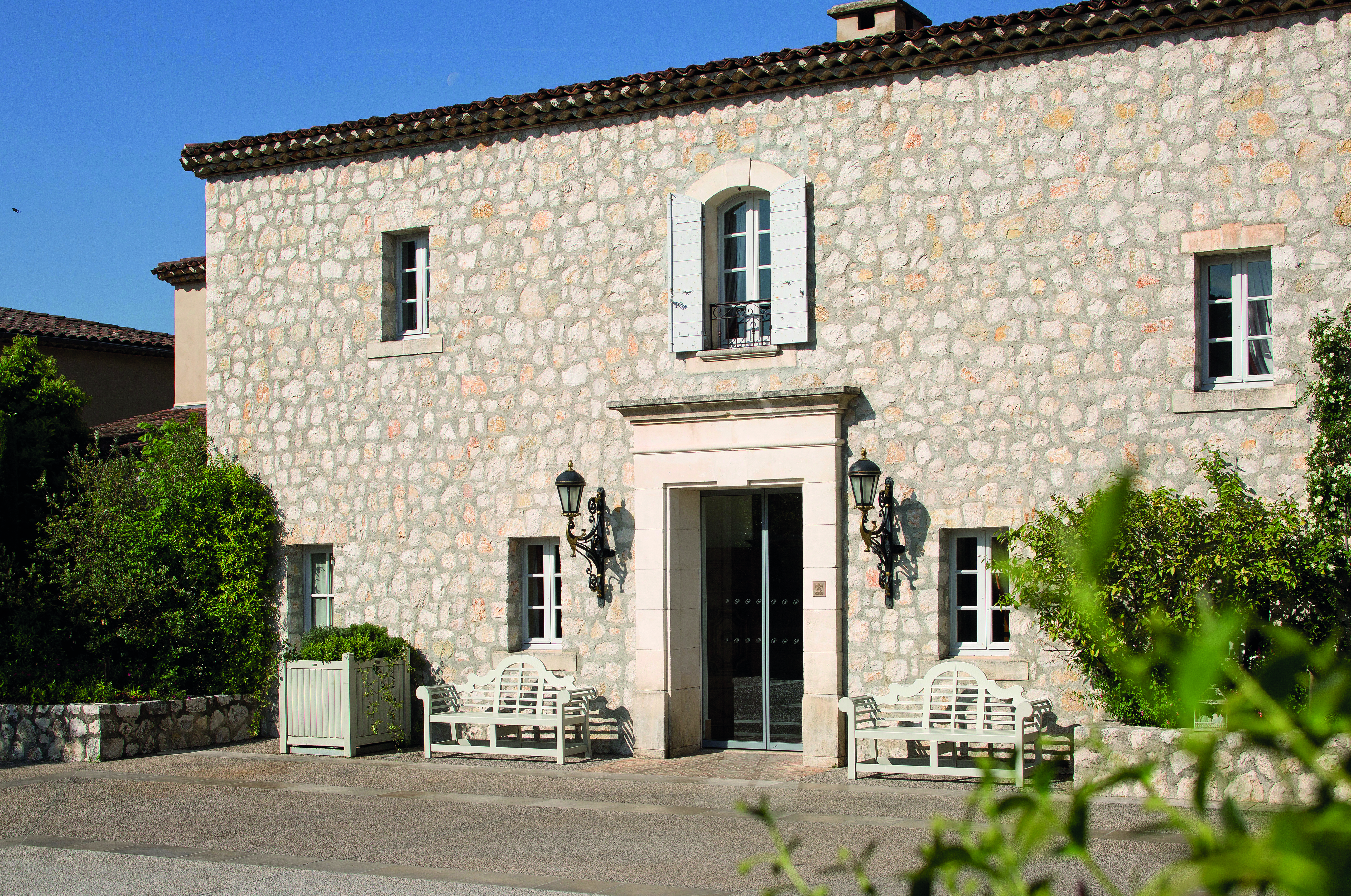 Le Mas de Pierre Cote d'Azur exterior large stone building with two wooden benches in front of it