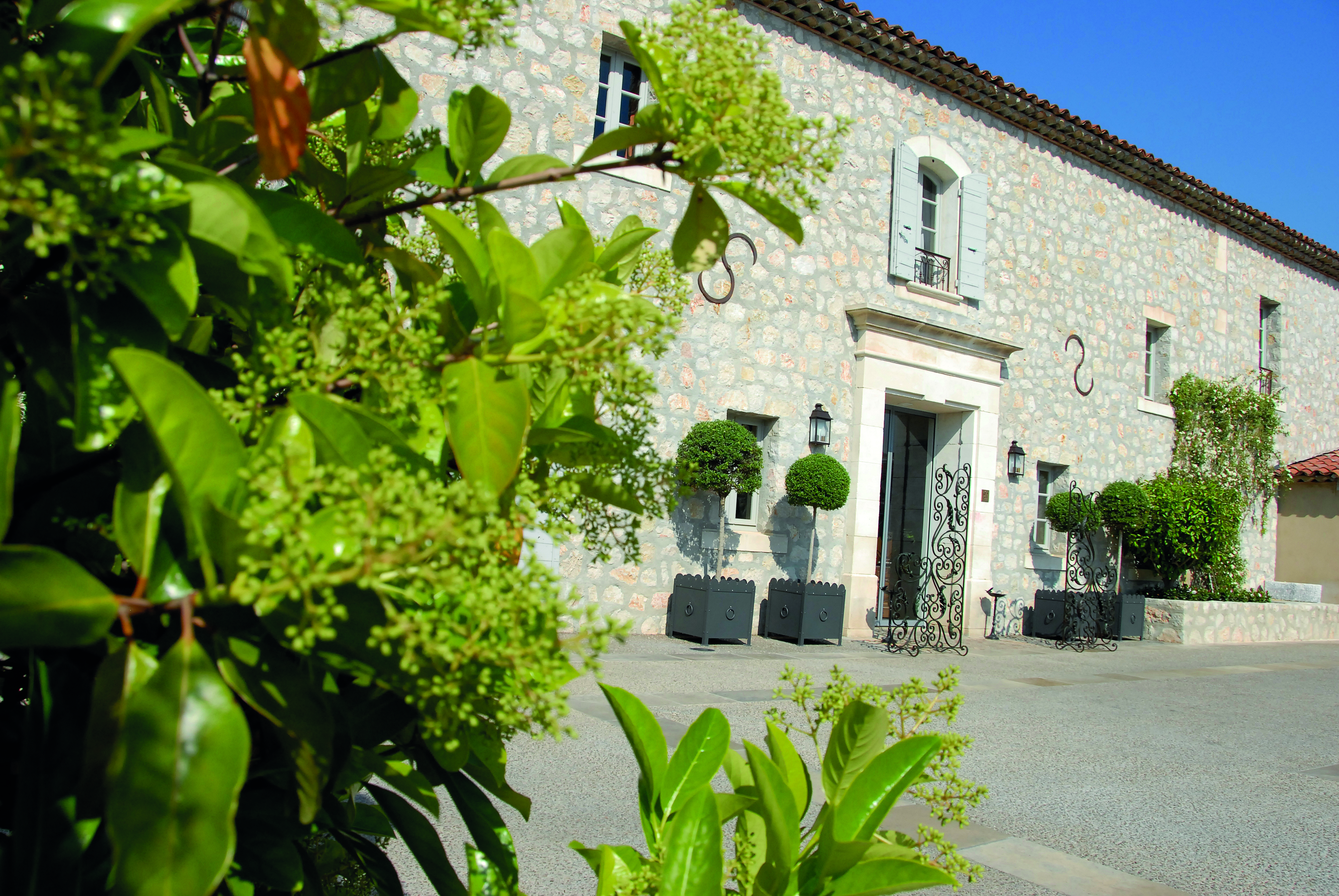 Le Mas de Pierre Cote d'Azur outdoor view large stone building with shutters wrought iron gate and topiary trees