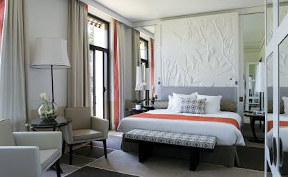 Royal Riviera Cote d'Azur deluxe sea garden bedroom with a grey headboard a white embossed floral wall