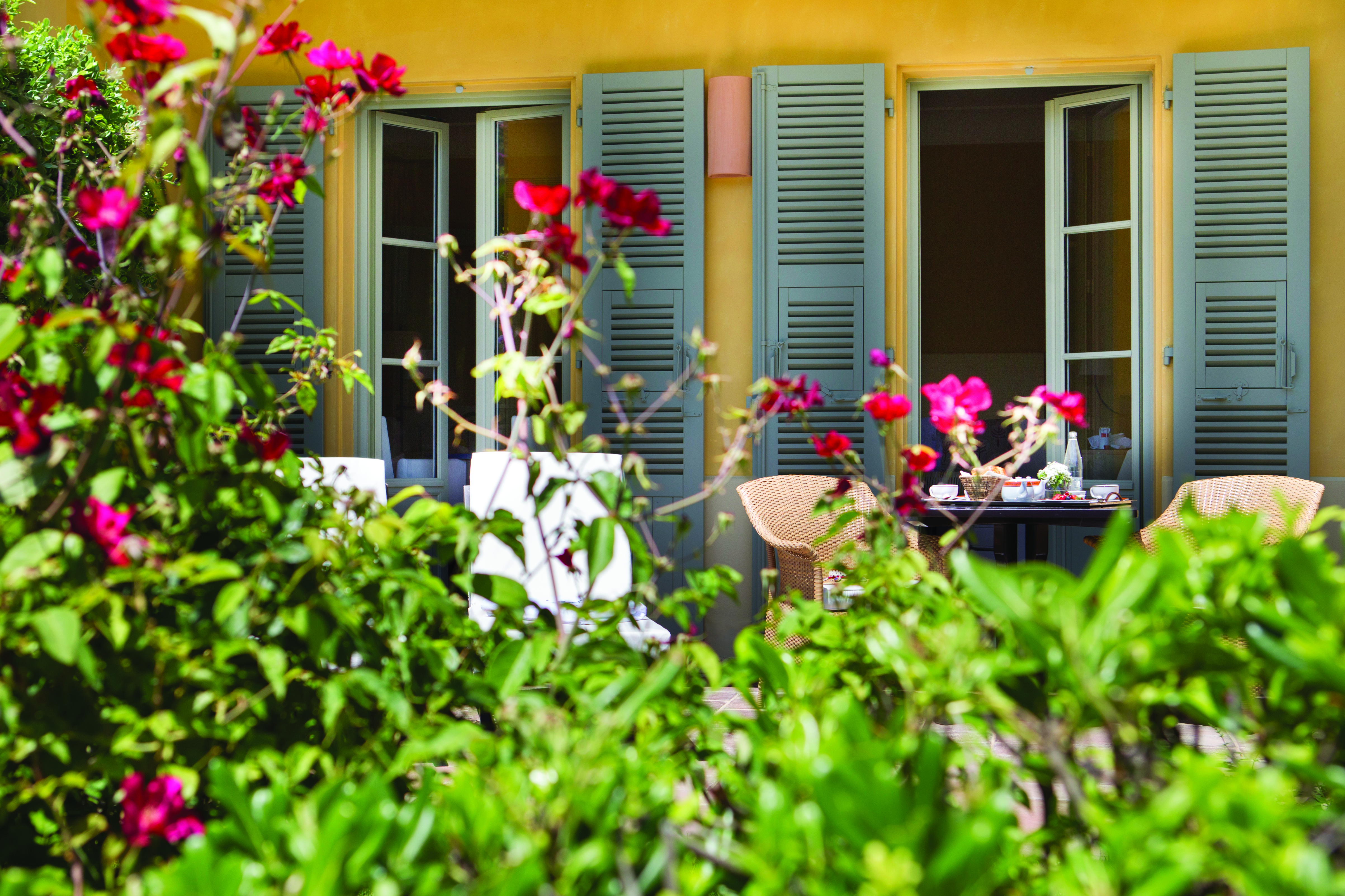 Royal Riviera Cote d'Azur orangerie terrace table outside a yellow building with blue shutters