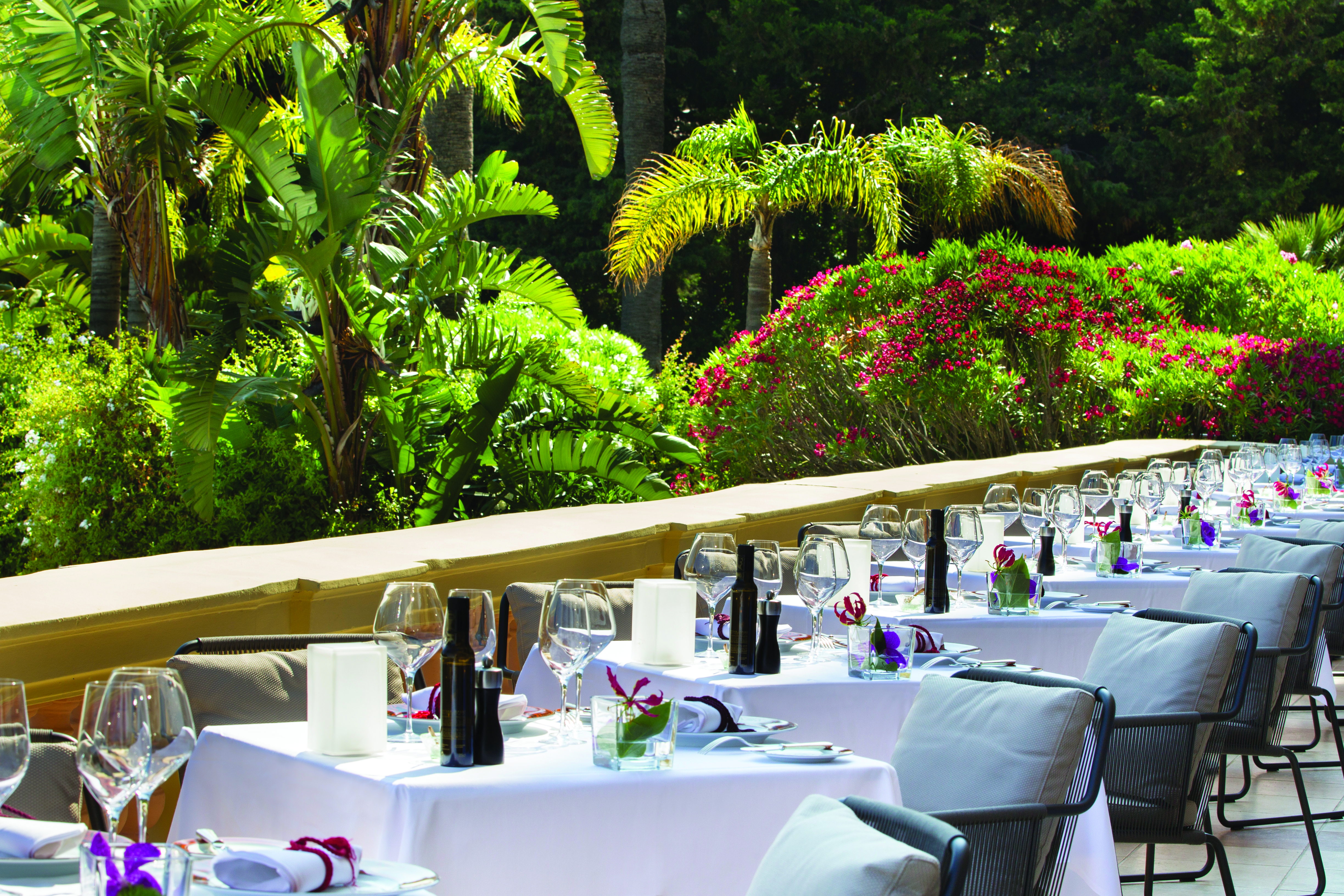 Royal Riviera Cote d'Azur garden view terrace tables with wine glasses overlooking garden and flowers