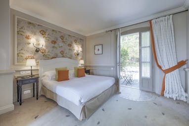 Le Mas Candille Cote d'Azur bedroom traditional decor with floral wall bedside tables armchair and door into a bathroom