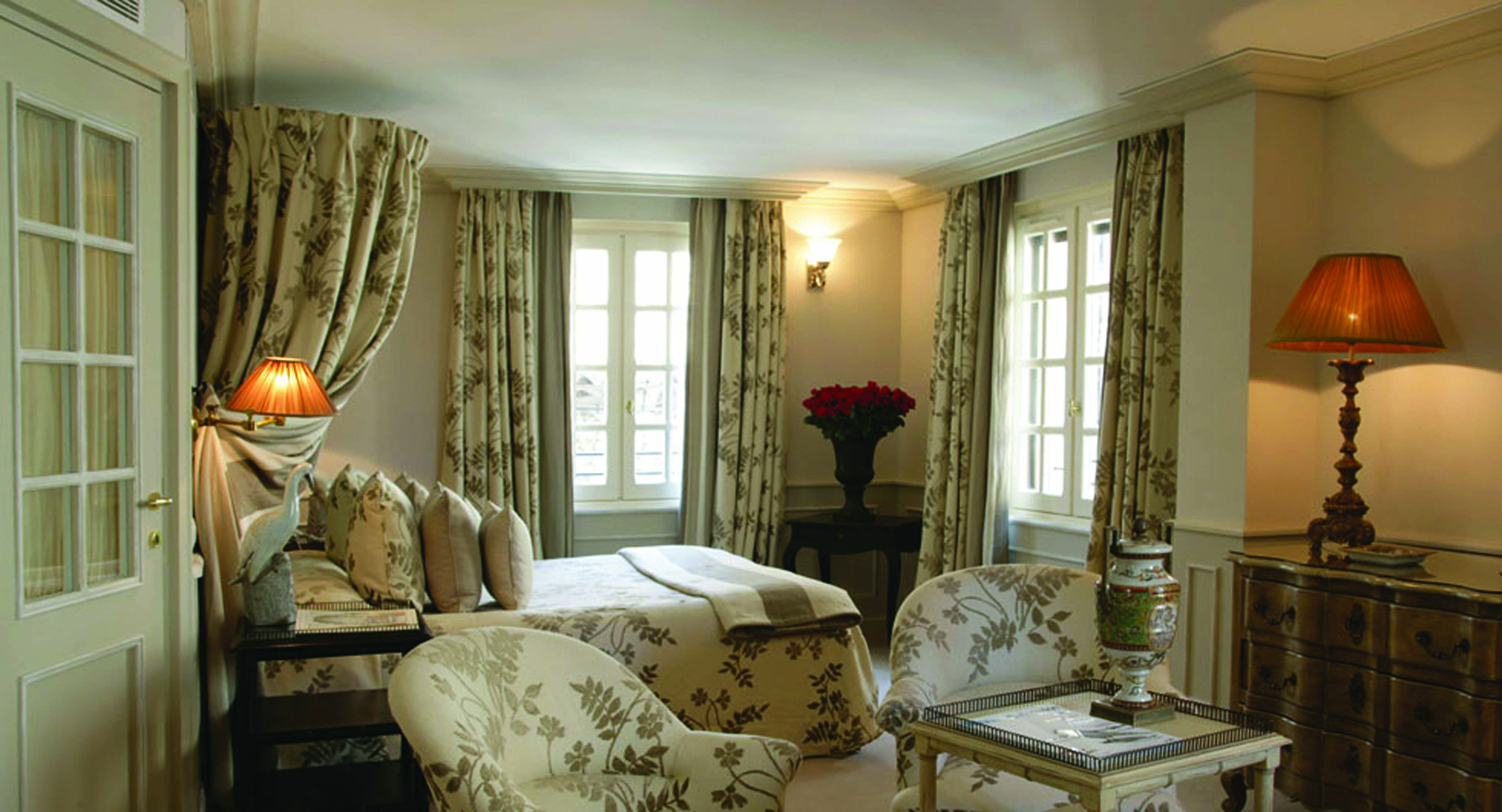 Le Saint Paul Cote d'Azur deluxe bedroom with drapes above bed with cream and grey floral pattern