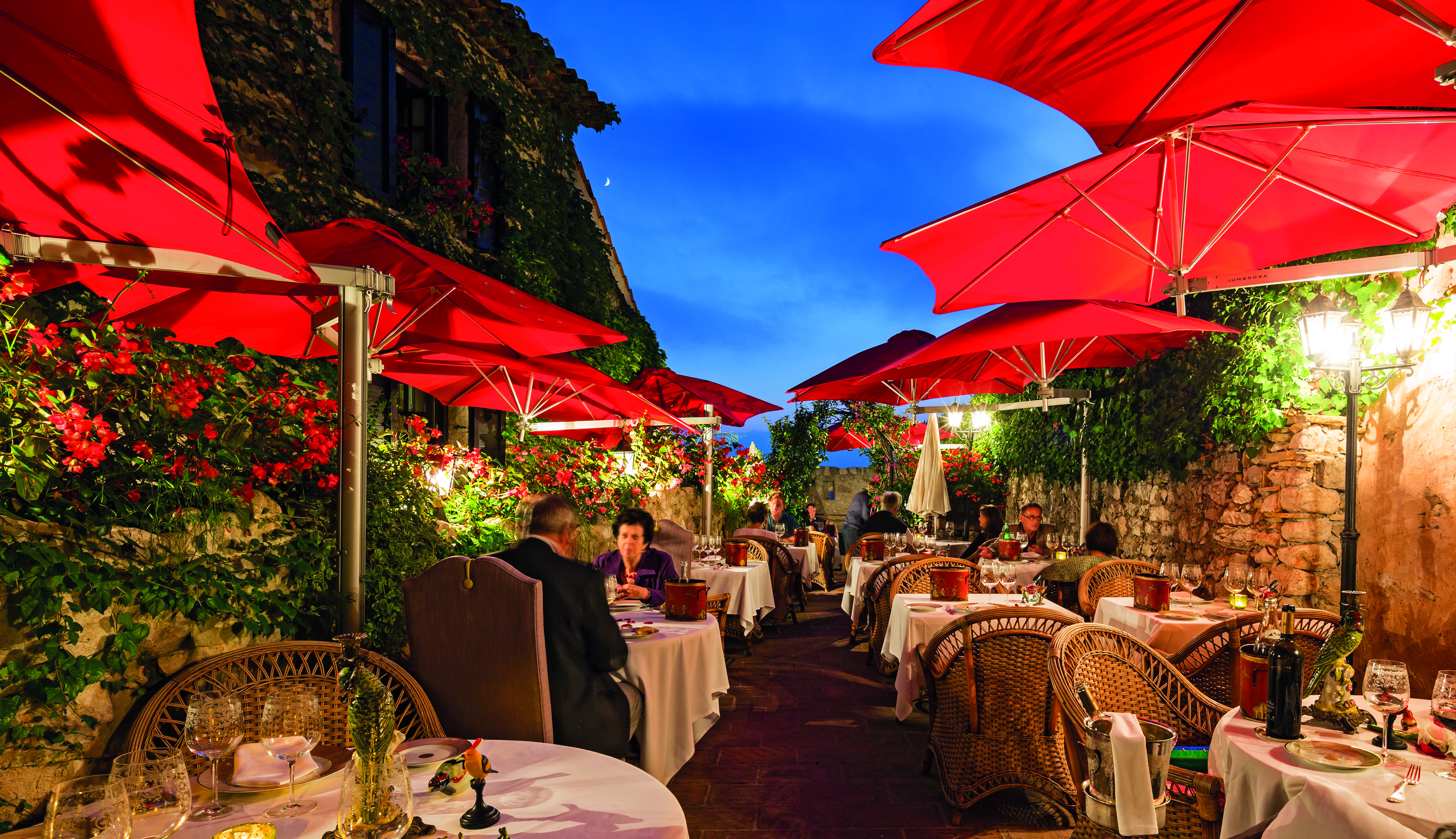 Le Saint Paul Cote d'Azur outdoor restaurant with umbrellas and red flowers