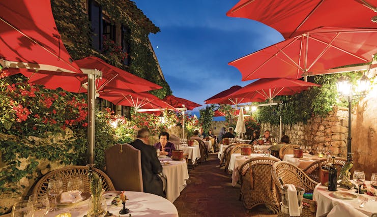 Le Saint Paul Cote d'Azur outdoor restaurant with umbrellas and red flowers
