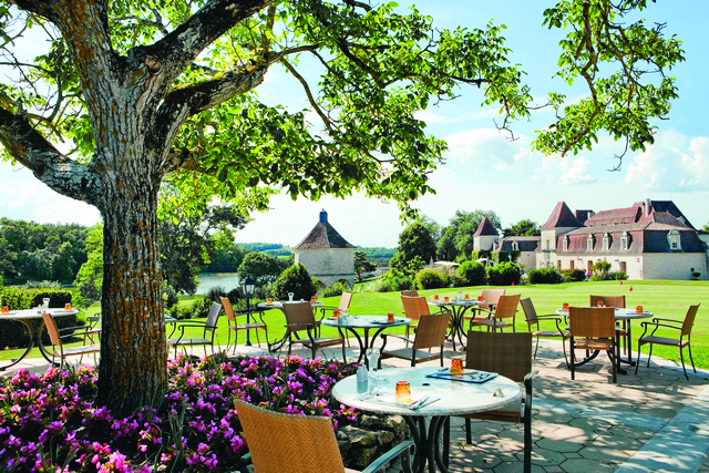 Chateau des Vigiers Dordogne brasserie chai dining area next to a tree and flower bed with pink flowers