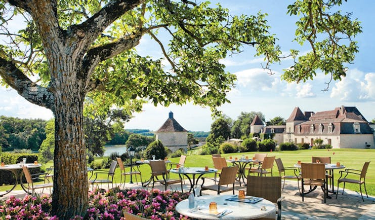 Chateau des Vigiers Dordogne brasserie chai dining area next to a tree and flower bed with pink flowers