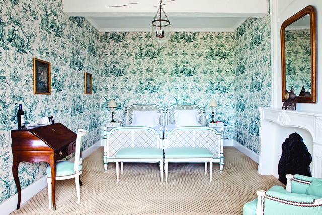 Chateau des Vigiers Dordogne deluxe blue room floral wallpaper and wooden writing bureau and fireplace