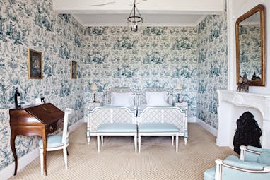 Chateau des Vigiers Dordogne deluxe blue room floral wallpaper and wooden writing bureau and fireplace