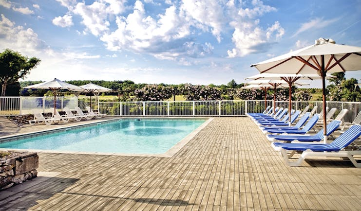 Chateau des Vigiers Dordogne outdoor heated pool with sun loungers and umbrellas