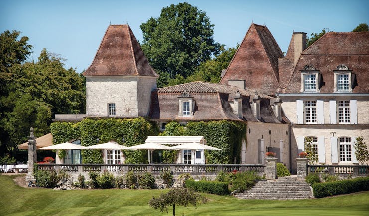 Chateau des Vigiers Dordogne outdoor large building foliage covered wall seating area with large white umbrellas