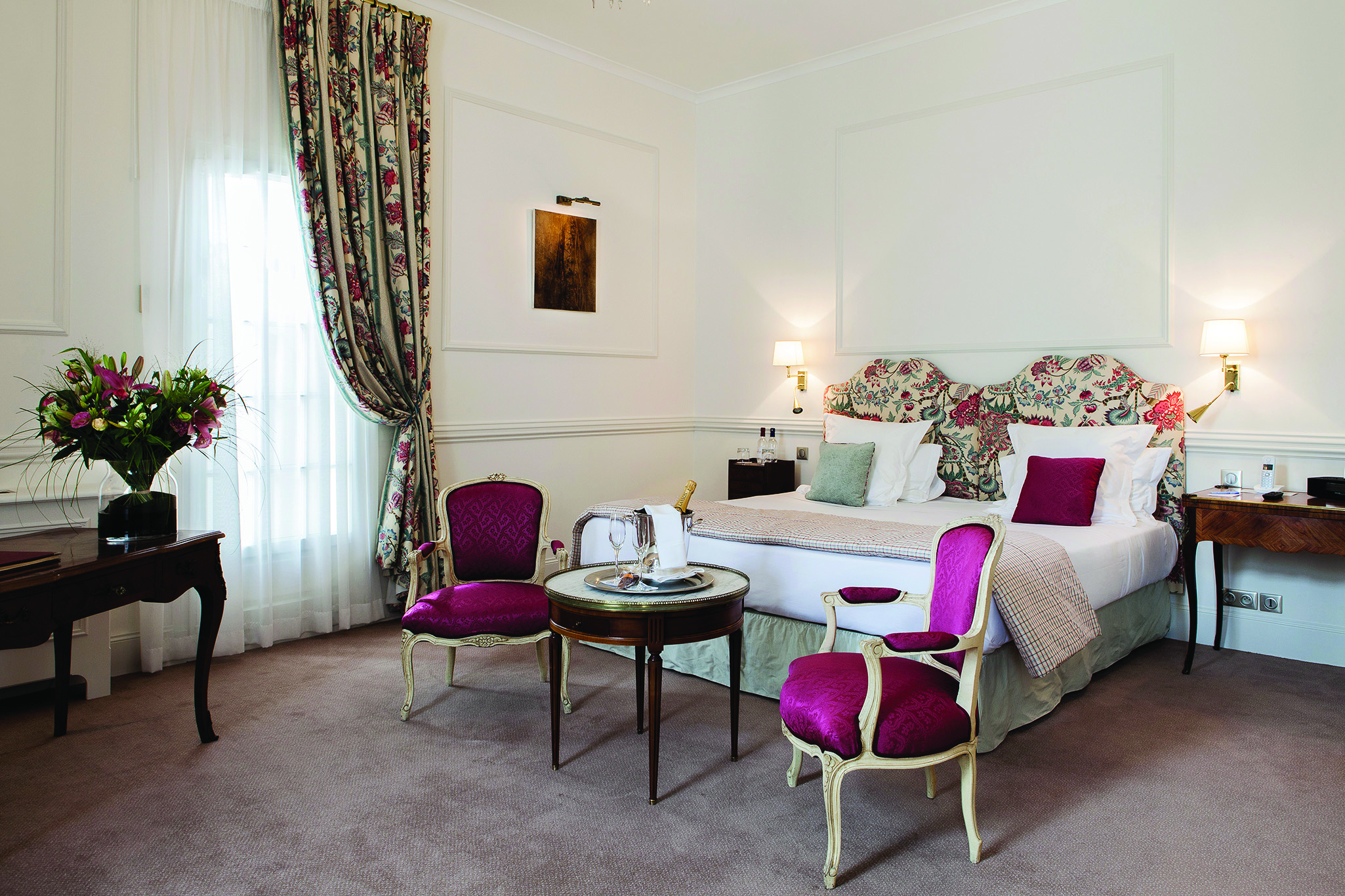 Chateau des Vigiers Dordogne prestige bedroom with floral bedhead two red chairs and table with wine