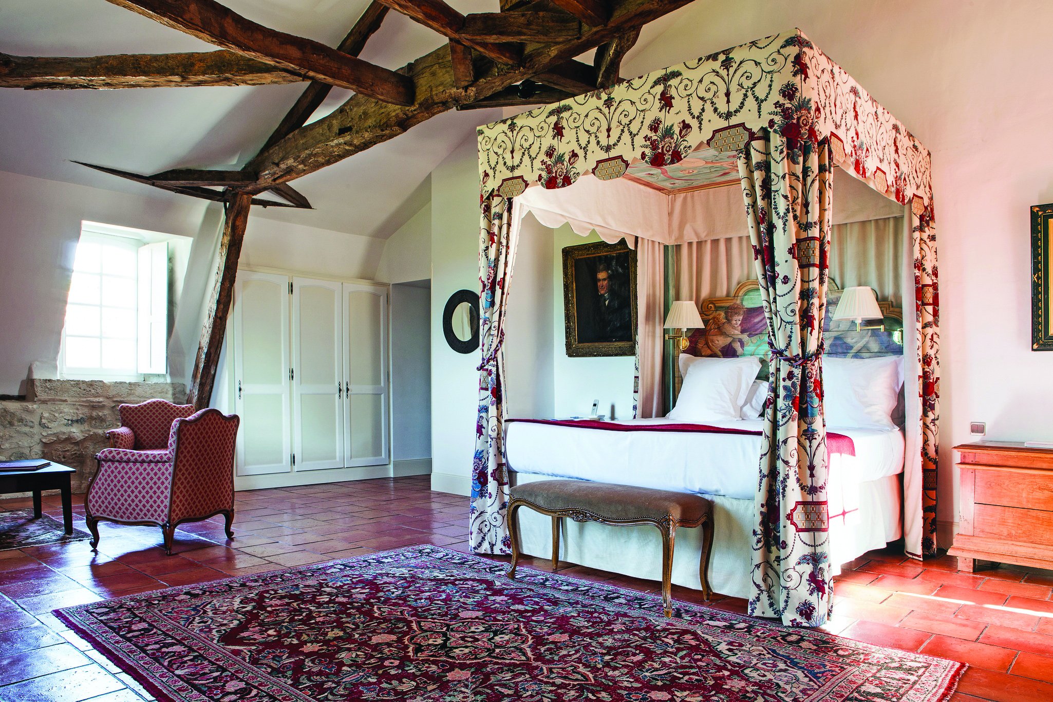 Chateau des Vigiers Dordogne prestige suite bedroom with exposed wooden beams four poster bed with floral canopy
