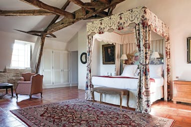 Chateau des Vigiers Dordogne prestige suite bedroom with exposed wooden beams four poster bed with floral canopy