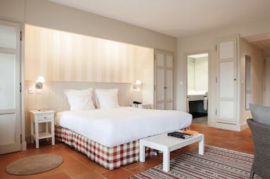 Chateau des Vigiers Dordogne relais superior bedroom with cream wooden panelled walls and a view to a bathroom