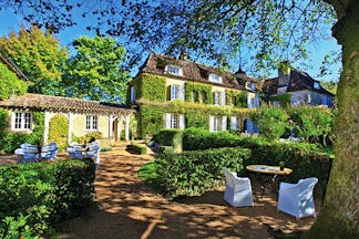 Le Vieux Logis Dordogne exterior large building covered in foliage overlooking tables and chairs