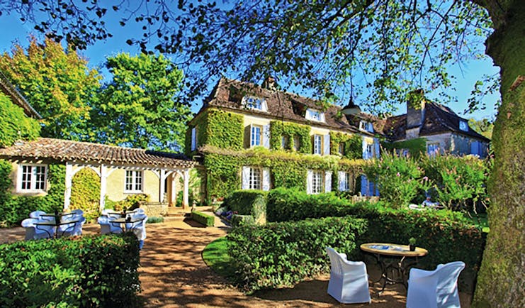 Le Vieux Logis Dordogne exterior large building covered in foliage overlooking tables and chairs