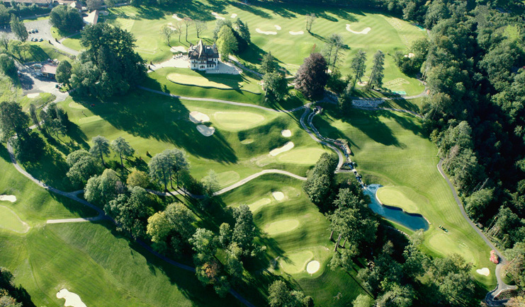 Hotel Ermitage Alps golf course surrounded by trees near a lake