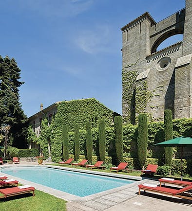 Hotel de la Cite Carcassonne Languedoc Roussillon pool with sun loungers umbrellas and topiary bushes