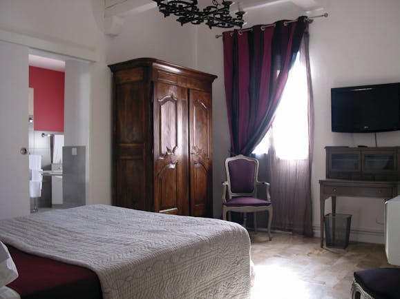 Relais des Chartreuses Languedoc Roussillon bedroom with bed desk television wardrobe and view into bathroom