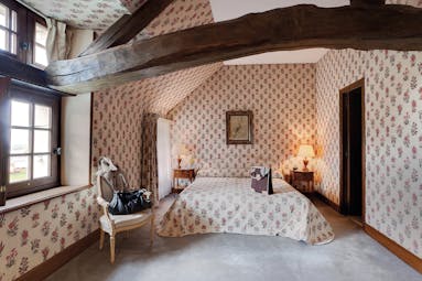 Chateau de Marcay Loire Valley bedroom with exposed wooden beams floral wallpaper and bedside tables
