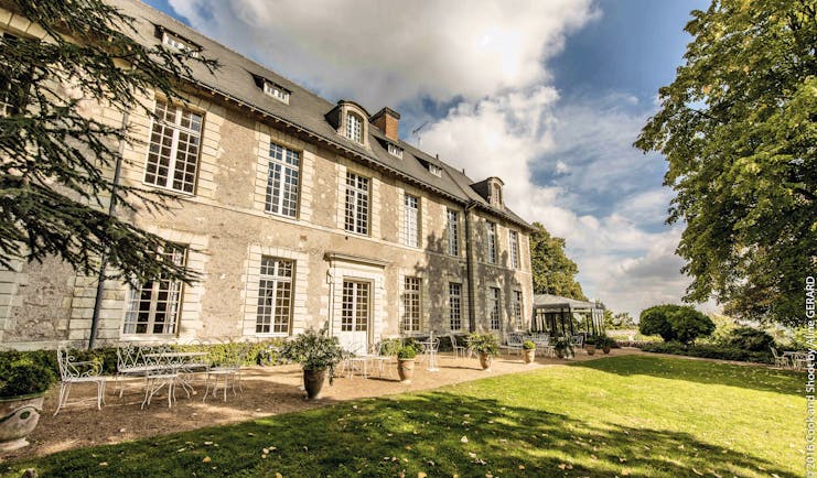Chateau Noirieux Loire Valley exterior shot stone chateau with large windows and white metal chairs 