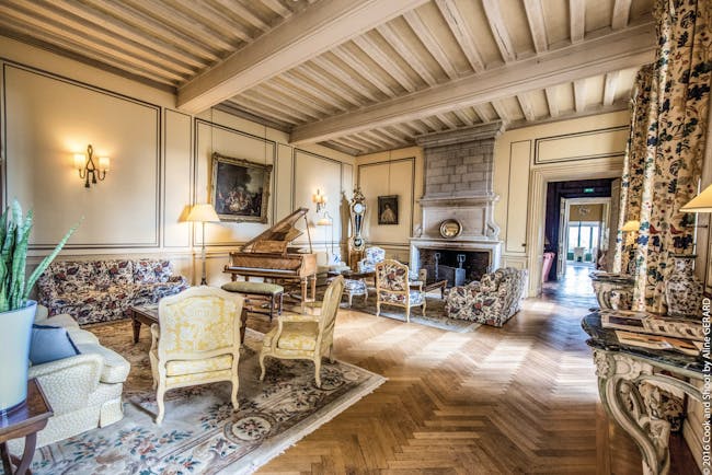Chateau Noirieux Loire Valley salon lounge area with armchairs grand piano and large fireplace