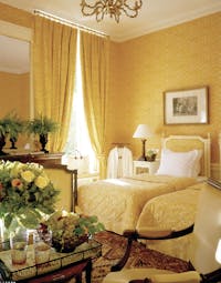 Bedroom decorated with a yellow colour scheme, two single beds and flowers arranged on a table